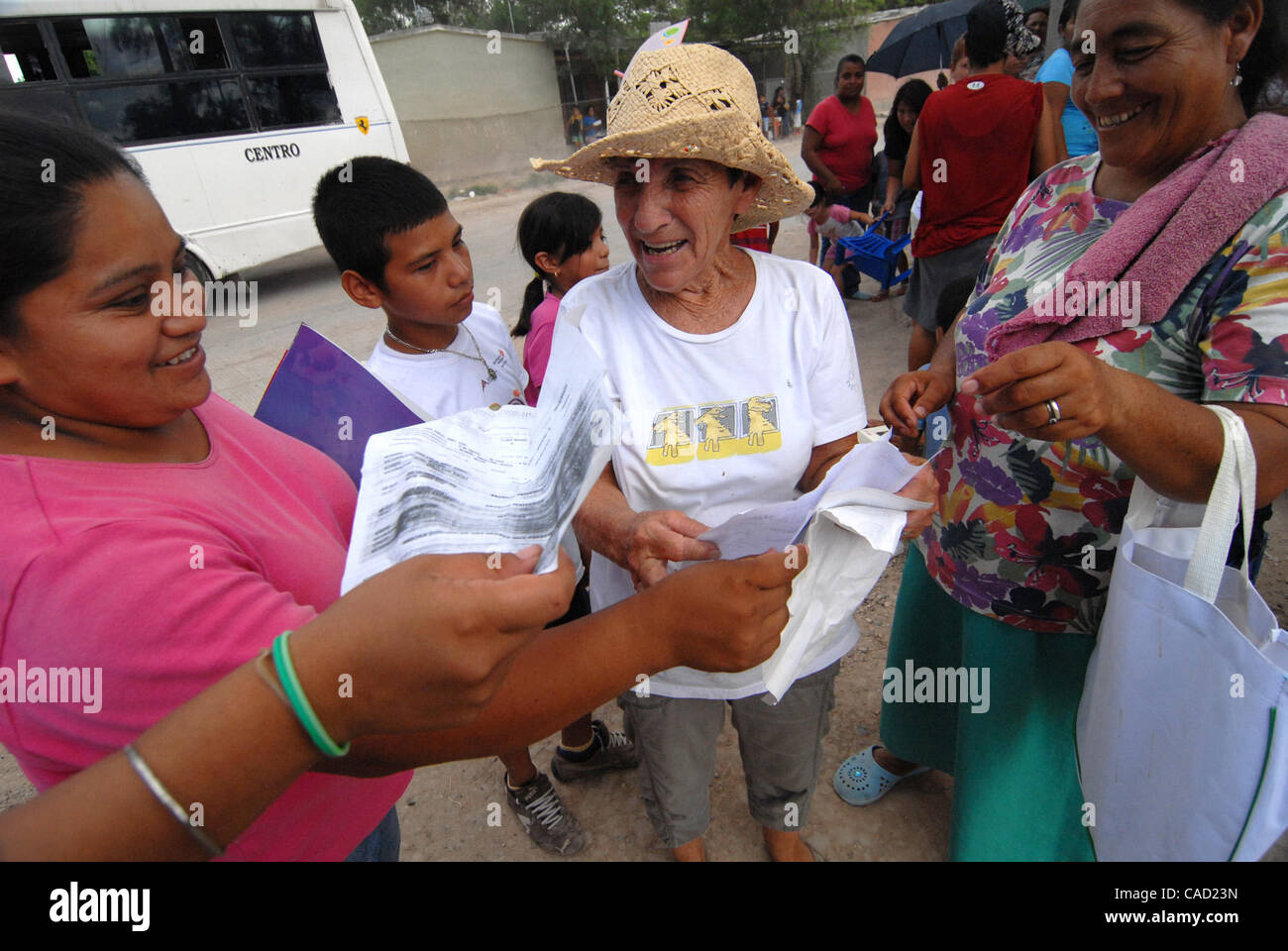 Aug 12, 2010 - Reynosa, Mexico - As she checks the line of residents that have gathered in the Colonia of Satelite Uno, DIANNE HURMAN is surrounded by smiling mothers giving her copies of birth certificates of their children, so that those children will recieve birthday cakes at the end of the day f Stock Photo