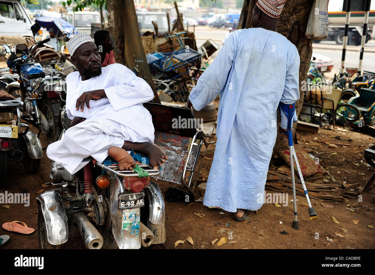 Aug. 5, 2010 - Kano, KANO, NIGERIA - Polio victim Sunusi Mohammad, lays on a custom modified motorcycle at the Kano State Polio Victims Trust Association in Kano, Nigeria. Right is Musa Mohammad, also with polio. Men with polio find community at the association..Religious zealotry and misinformation Stock Photo