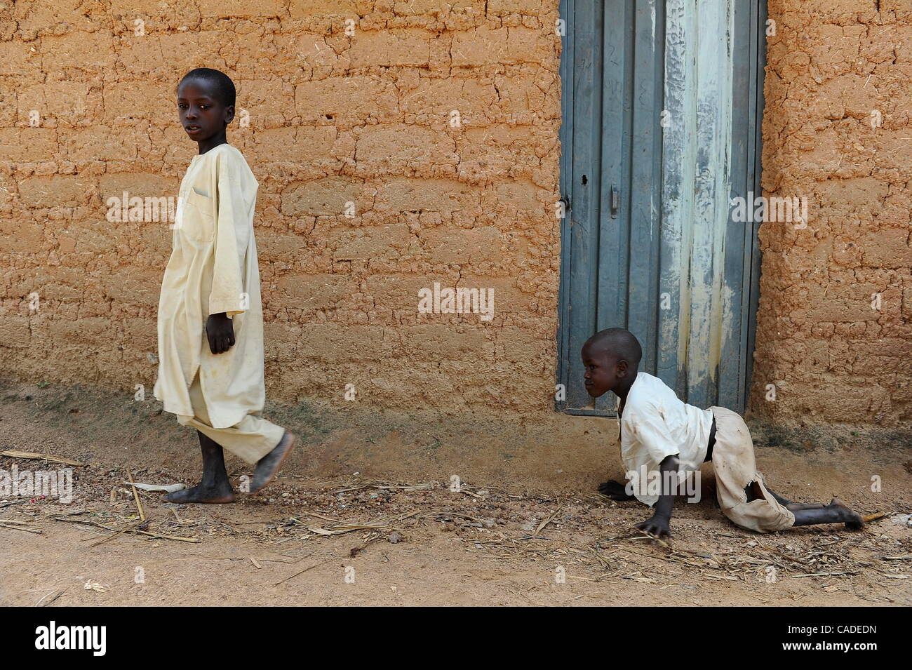 Sept. 20, 2010 - Rimin-Gado, KANO, NIGERIA - Polio victim Abubakar, 6, right, follows a boy in his neighborhood near Kano, Nigeria. Religious zealotry and misinformation have coerced villagers in the Muslim north of Nigeria into refusing polio vaccinations and led to the reemergence of polio only a  Stock Photo