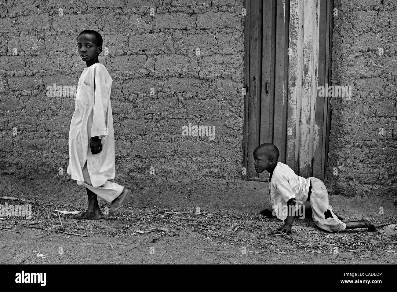 Sept. 20, 2010 - Rimin-Gado, KANO, NIGERIA - Polio victim Abubakar, 6, right, follows a boy in his neighborhood near Kano, Nigeria. Religious zealotry and misinformation have coerced villagers in the Muslim north of Nigeria into refusing polio vaccinations and led to the reemergence of polio only a  Stock Photo