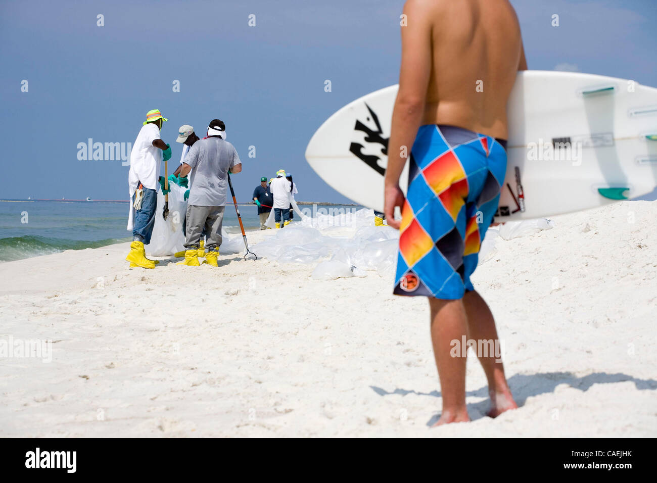 Jun 18, 2010 - Gulf Shores, Alabama, U.S. - Surfer walking through beach clean up at Gulf Shores, Alabama. The Deepwater Horizon oil spill is a massive ongoing oil spill in the Gulf of Mexico, now considered the largest offshore spill in U.S. history. The spill stems from a sea floor oil gusher that Stock Photo