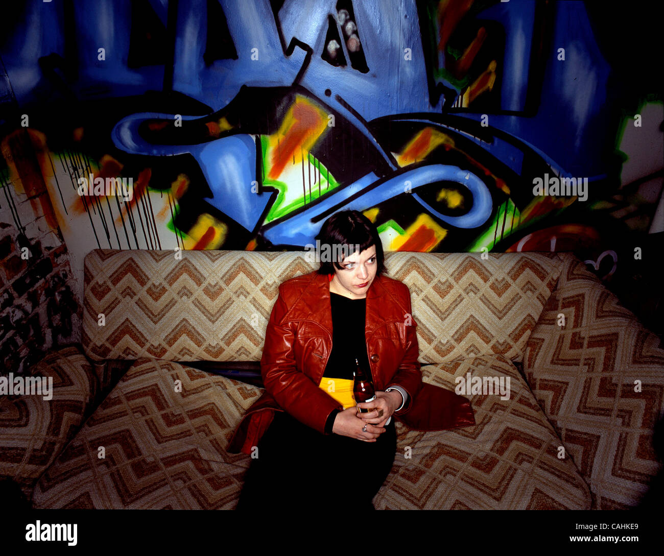 THIS WAS SHOT IN  DECEMBER OF 2007 IN CHICAGO. I WAS SHOOTING A BAND IN A BASEMENT AT A SHOW. I HAD JESSICA A FRIEND OF MINE SIT IN BECAUSE OF THE GRAFFITT ON THE WALL AND THE CLOTHES SHE HAD ON. MY FRIEND JOE DID ALL OF THE GRAFITTI AND THE HAD THIS OLD COUCH DOWN THERE,IT WAS PERFECT. Stock Photo