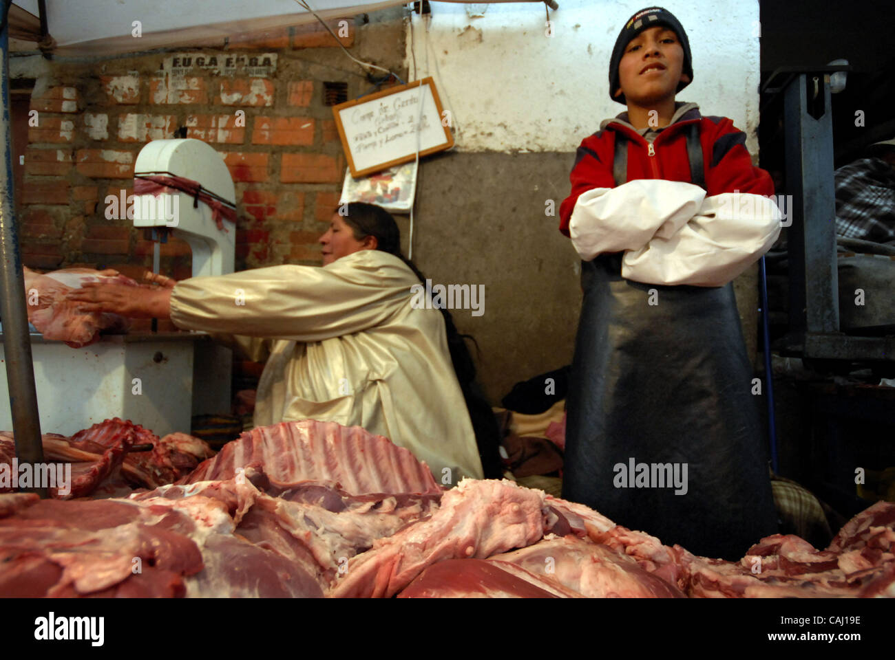 Dec 31, 2007 - La Paz, Bolivia - A young boy helps his grand mother to sell pork meat in La Paz Garita de Lima's street market. Every 31st December in La Paz, thousands of dead pigs are brought to the city to be sold, coming from Cochabamba, Santa Cruz and all La Paz areas. The bolivian tradition to Stock Photo