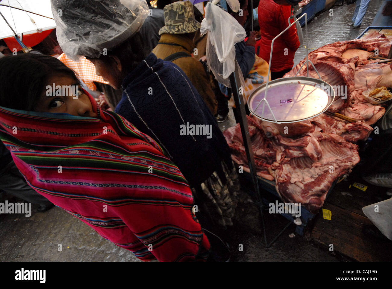 Dec 31, 2007 - La Paz, Bolivia - A young indigenous girl waits to buy her pork meat in La Paz Garita de Lima's street market. Every 31st December in La Paz, thousands of dead pigs are brought to the city to be sold, coming from Cochabamba, Santa Cruz and all La Paz areas. The bolivian tradition to e Stock Photo