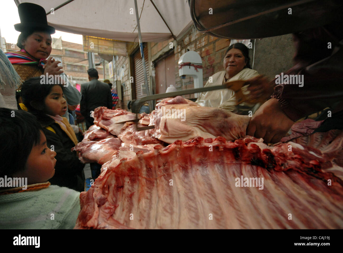 Dec 31, 2007 - La Paz, Bolivia - A family waits for their pork meat to be cut in La Paz Garita de Lima's street market. Every 31st December in La Paz, thousands of dead pigs are brought to the city to be sold, coming from Cochabamba, Santa Cruz and all La Paz areas. The bolivian tradition to eat por Stock Photo