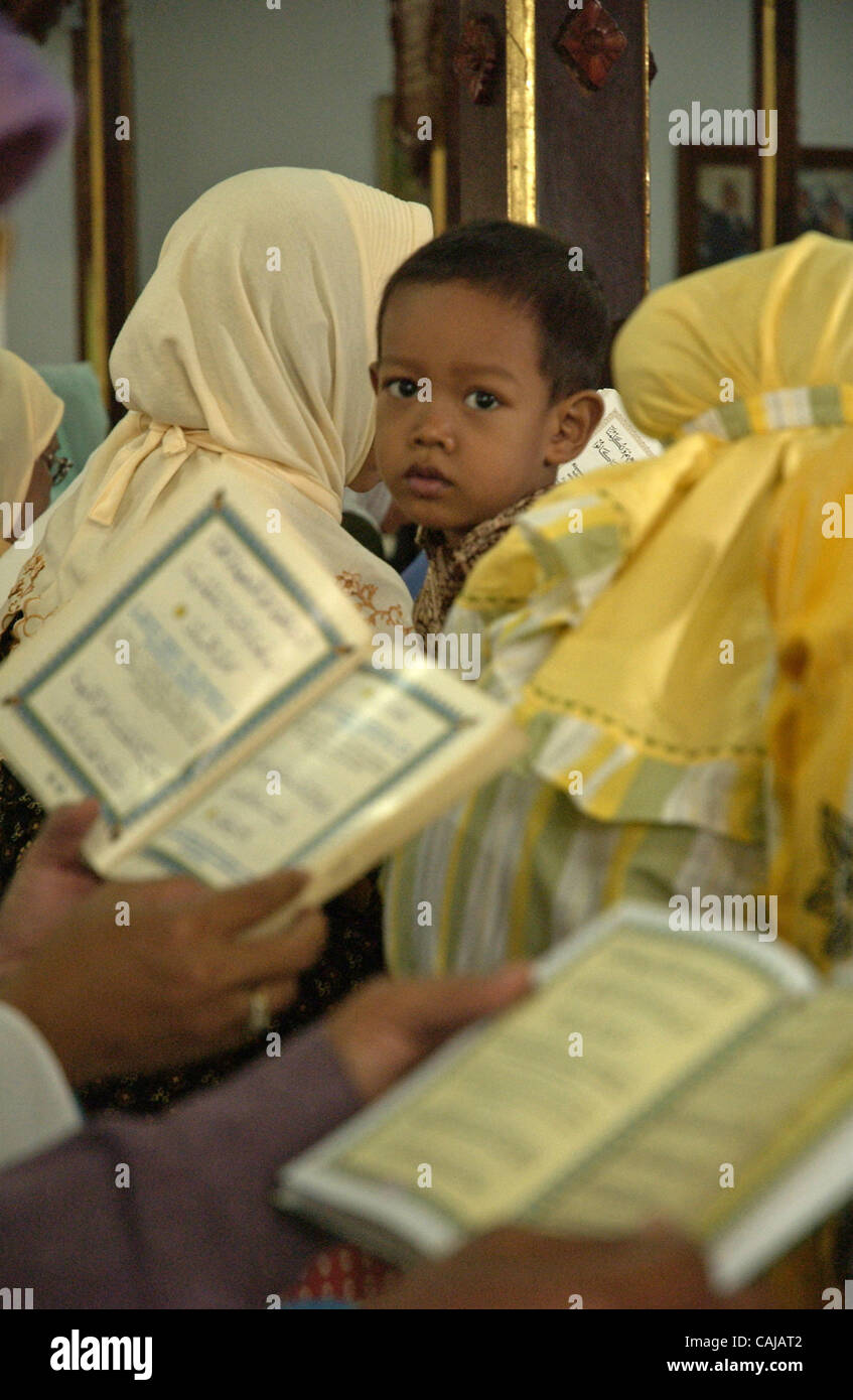 SOLO, CENTRAL JAVA, INDONESIA-JANUARY 14,2008:  Women read Koran as accompanied by her kid at ndalem Kalitan, a family coumpound of suharto's late wife. Residents pray inside the coumpound to pray for better condition of the former Indonesian president after he suffered multiple organs failure.  Pho Stock Photo