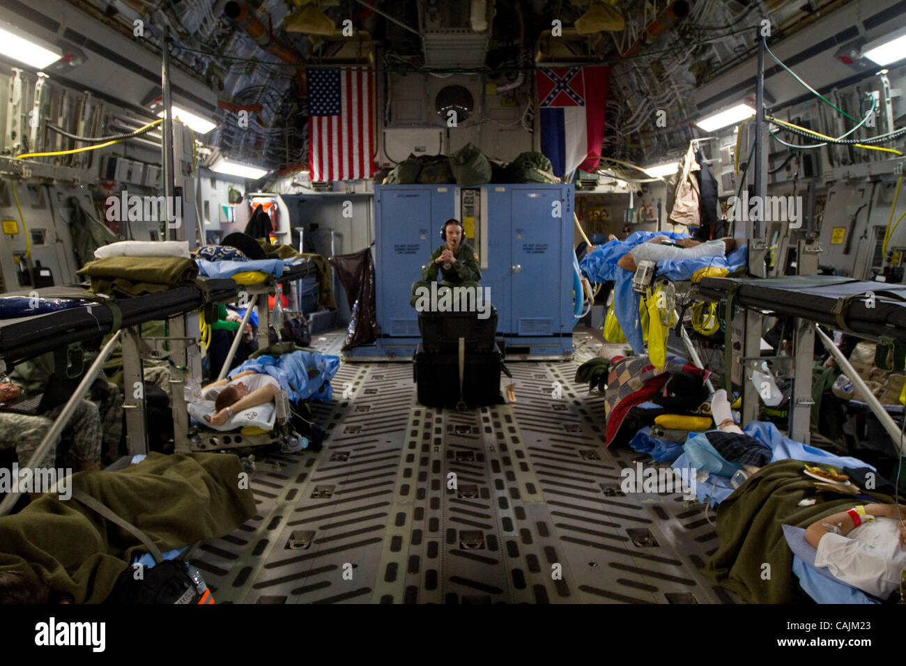 AF Senior Airman, Audrey Gordon, medical technician assigned to the 86th AES (Aeromedical Evacuation Squadron) based in Ramstein, Air Base, Germany, sits atop boxes as she monitors a group of seriously injured soldiers wounded in Afghanistan  aboard a Mississippi Air National Guard C-17 cargo plane  Stock Photo