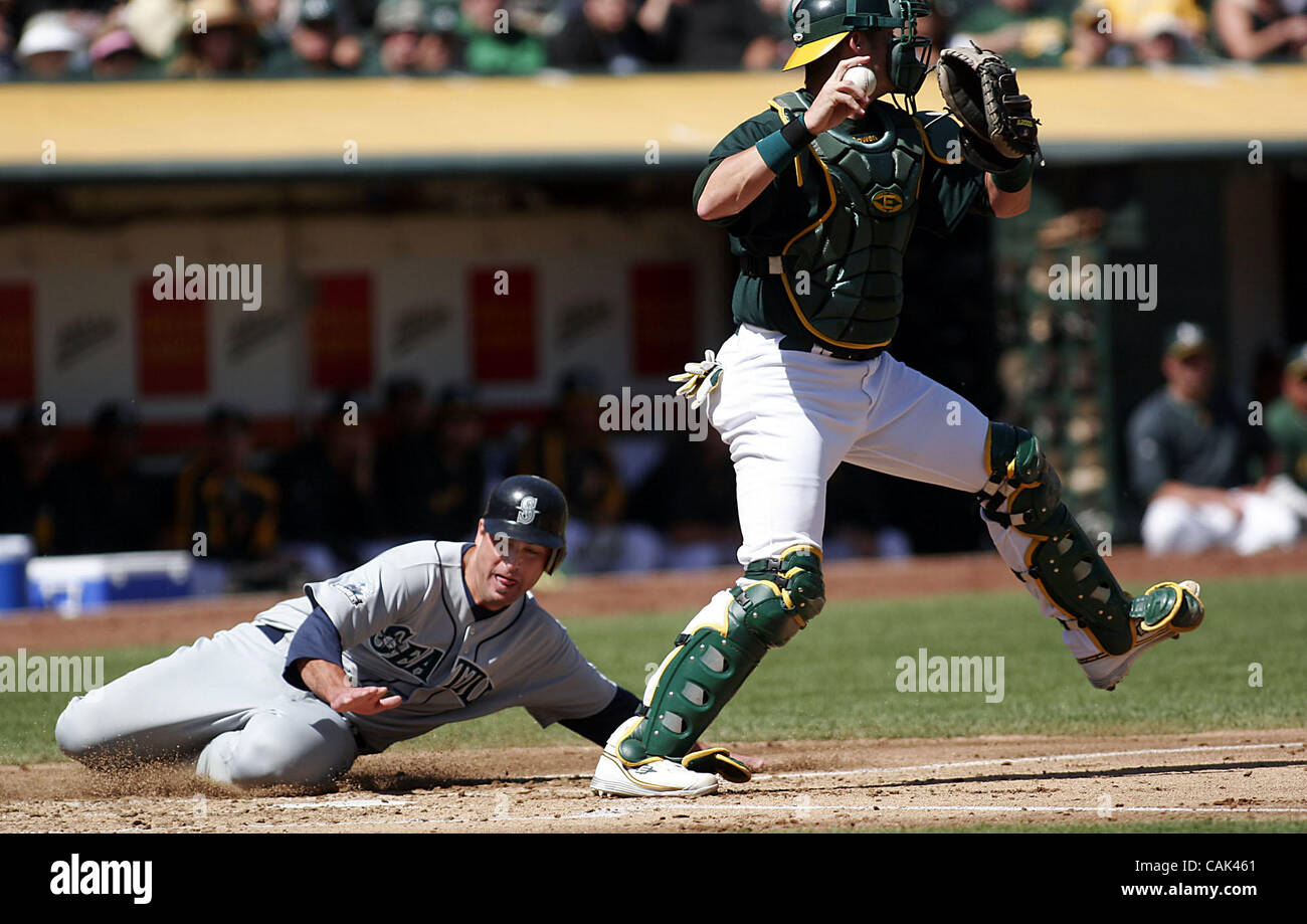 Mariners' catcher Jamie Burke (left) slides safely into home as A's
