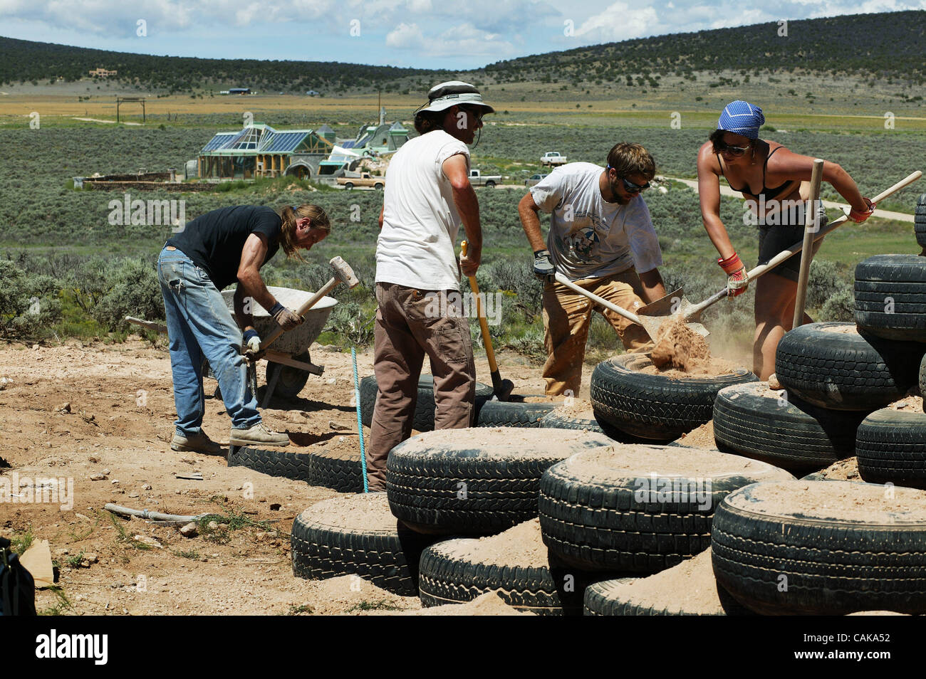 Workers pack dirt into tire foundation walls in the Greater World