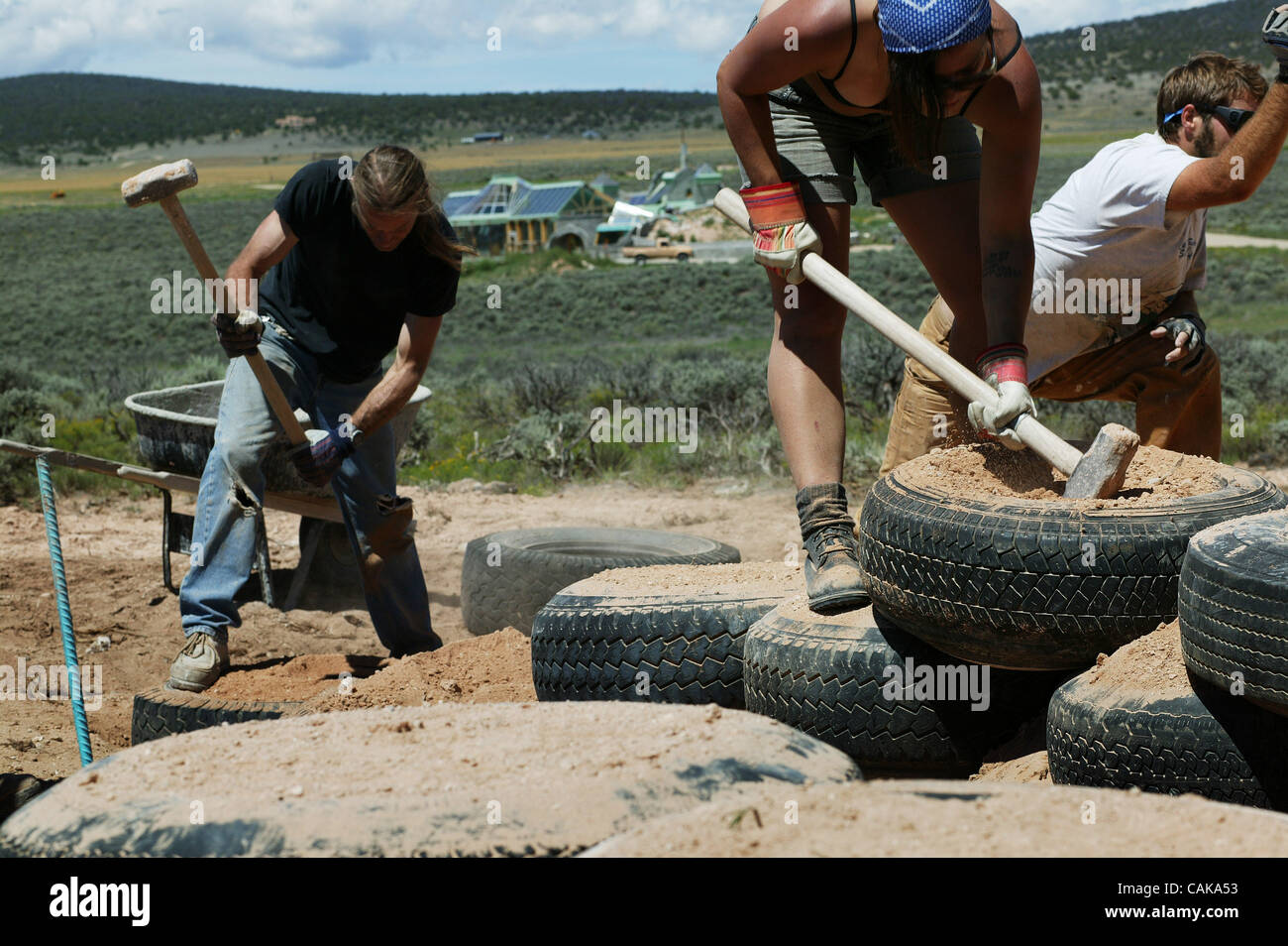 Workers pack dirt into tire foundation walls in the Greater World