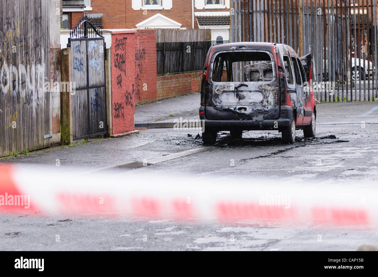 A burned out van is cordoned off by police after it was involved in a crime. Stock Photo