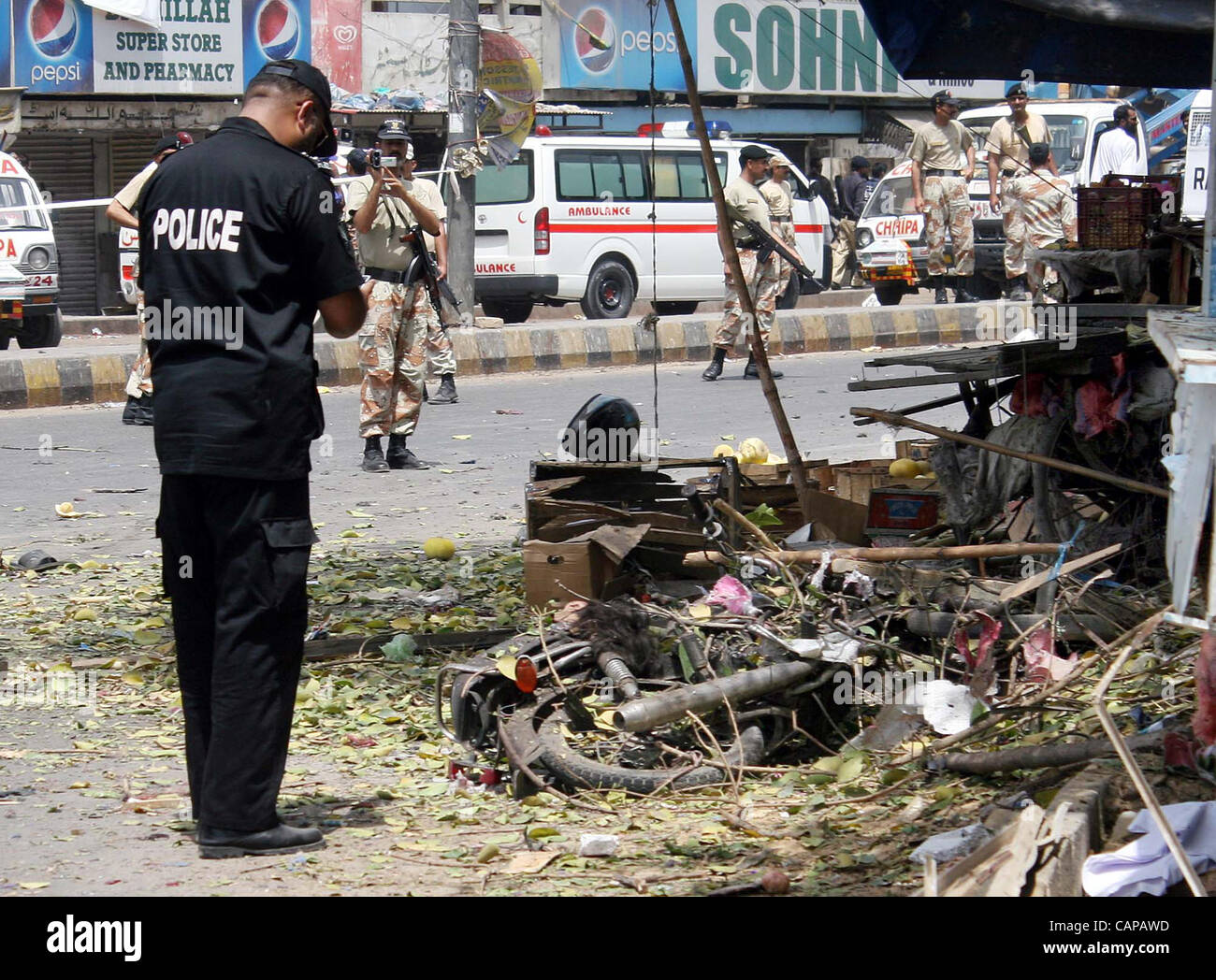 Security official gather at a damaged motorcycle, which was used in explosion, at the site of explosion after explosion in Karachi on Thursday, April 05, 2012. Atleast four people including two policemen were killed while fourteen people were wounded when a suicide bomber Stock Photo