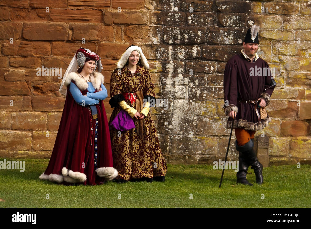 Two women and a man dressed in medieval clothes watch the battle at the ...