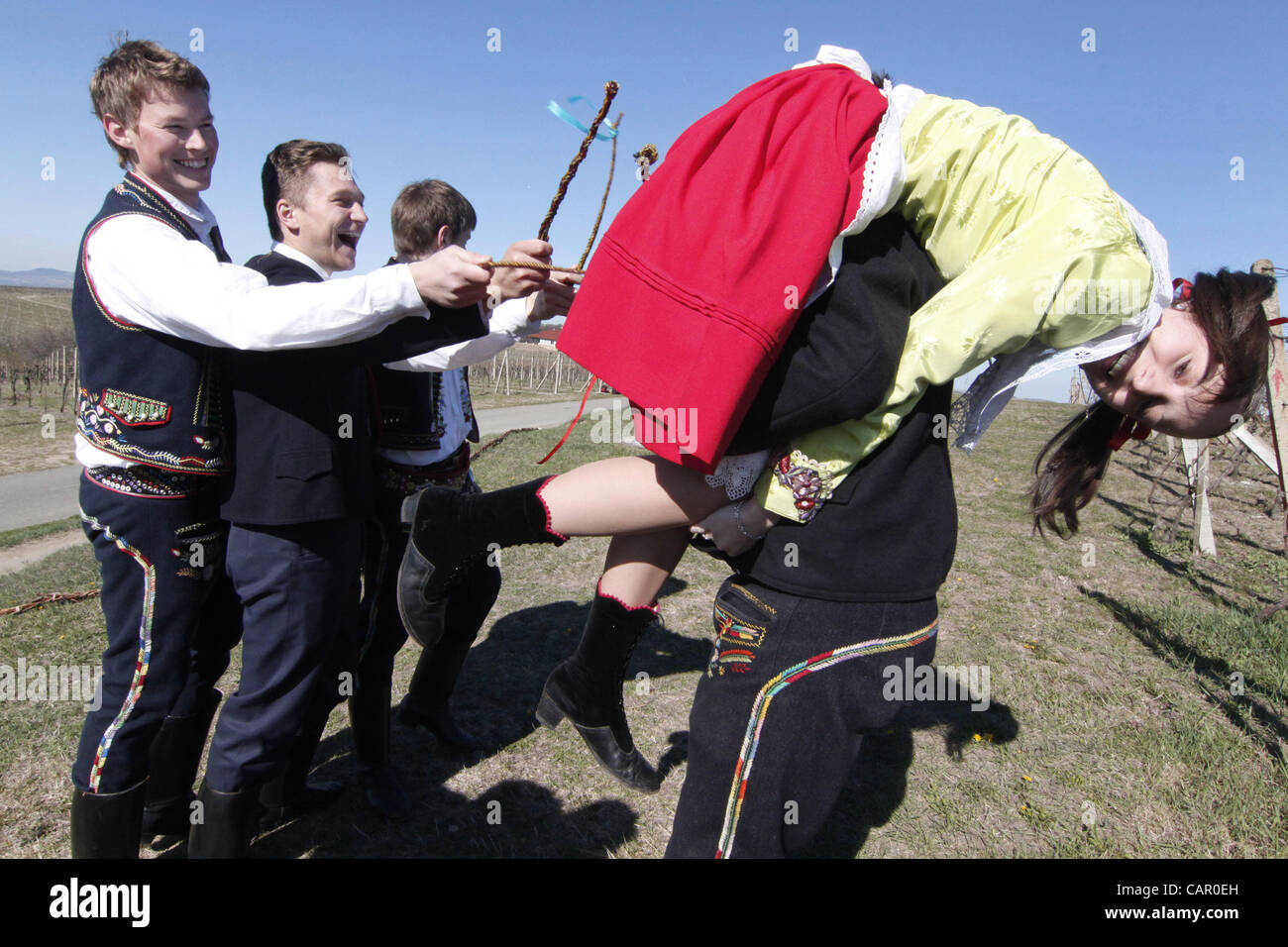 Boys in folk customs carry a giant "pomlazka" (plated willow stems) to whip girls during traditional celebration of Easter Monday in Nemcicky, South Moravia, on Monday, April 9, 2012. The tradition of whipping girls and women with plaited willow stems and splashing them with cold water should assure Stock Photo