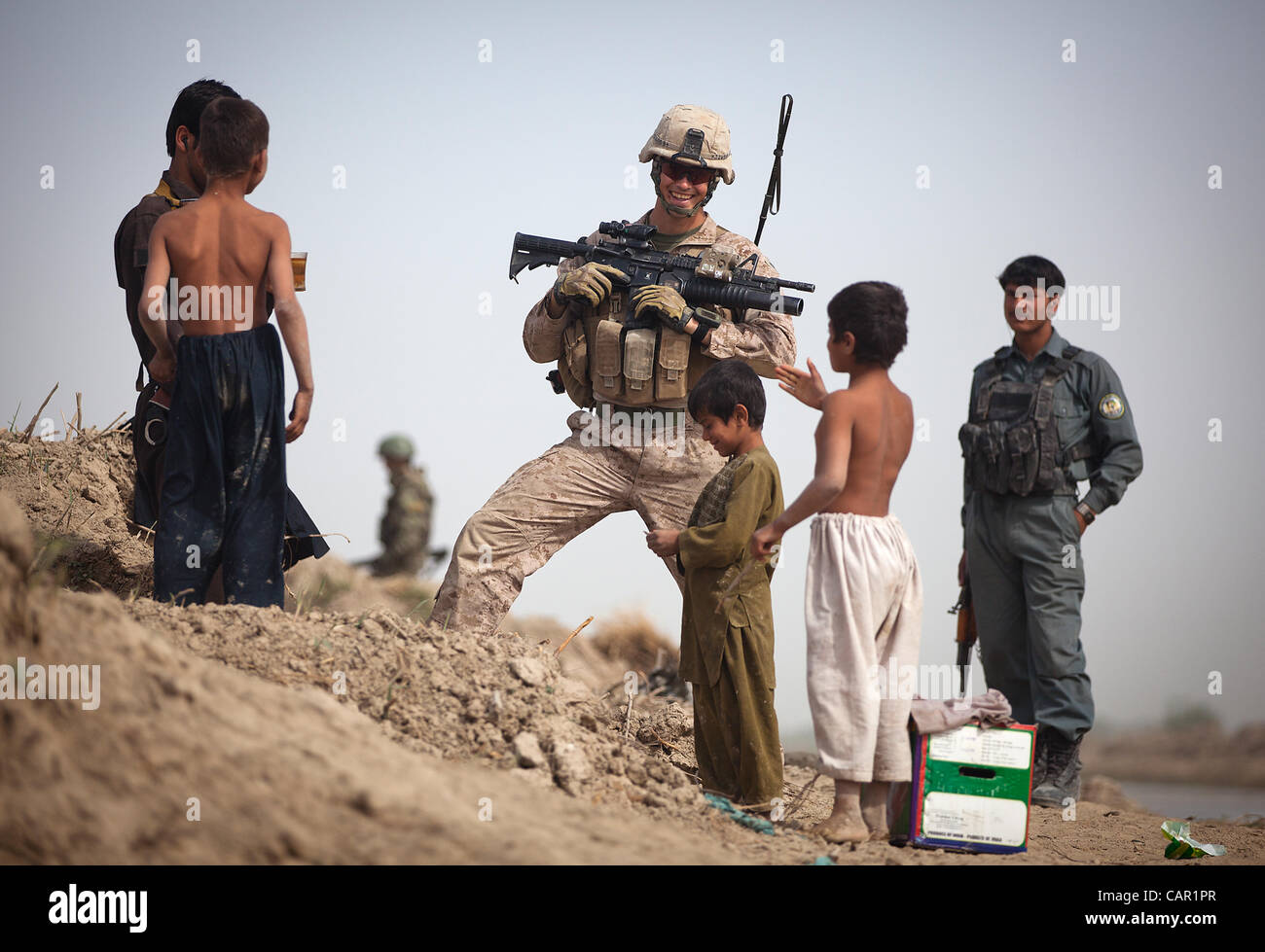 U.S. Marine Cpl. Mark Jensen (center), a team leader with 4th Platoon, Kilo Company, 3rd Battalion, 3rd Marine Regiment, and 22-year-old native of Nyssa, Ore., talks with Afghan National Police patrolmen and local children while providing security at a vehicle checkpoint. Stock Photo