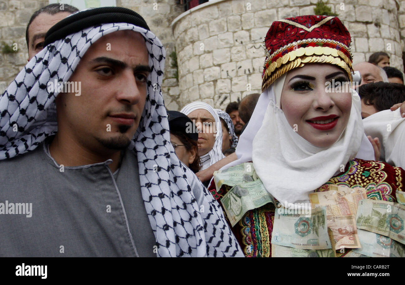 April 12, 2012 - Nablus, West Bank, Palestinian Territory - The Palestinian, bride, MHAHA SALAM and, groom, THAYER QASEM walk down the street on their wedding day  after they traveled from the refugee camp of al-Yarmuk in Syria, to get married in the West Bank village of Deir Estia. Stock Photo