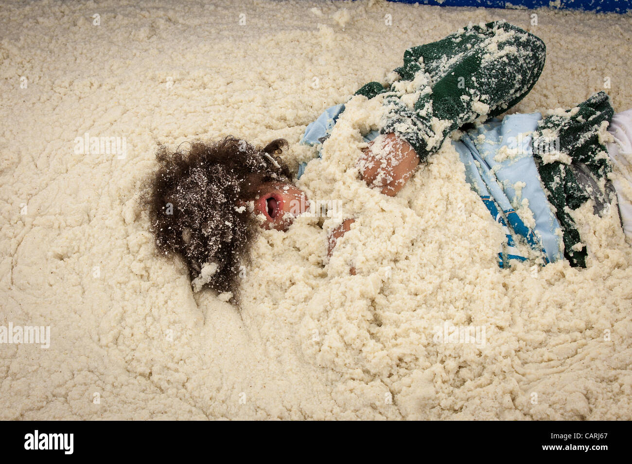 A competitor rolls around in a pool of instant grits during the grits