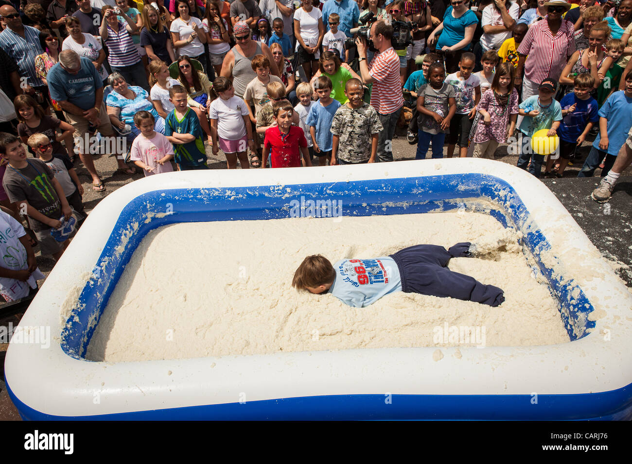 A competitor rolls around in a pool of instant grits during the grits