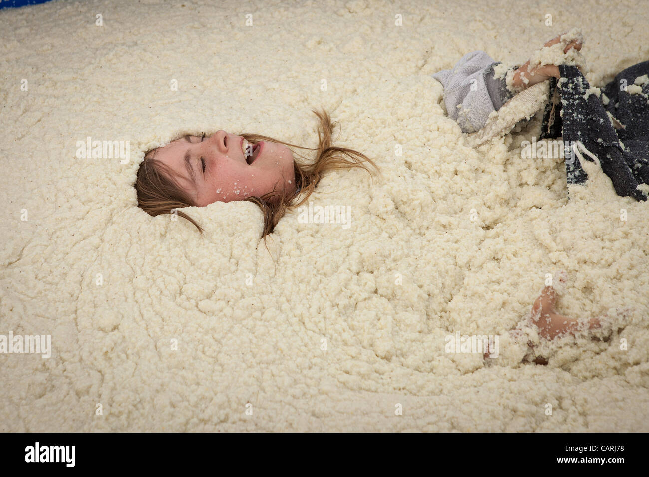 A competitor rolls around in a pool of instant grits during the grits