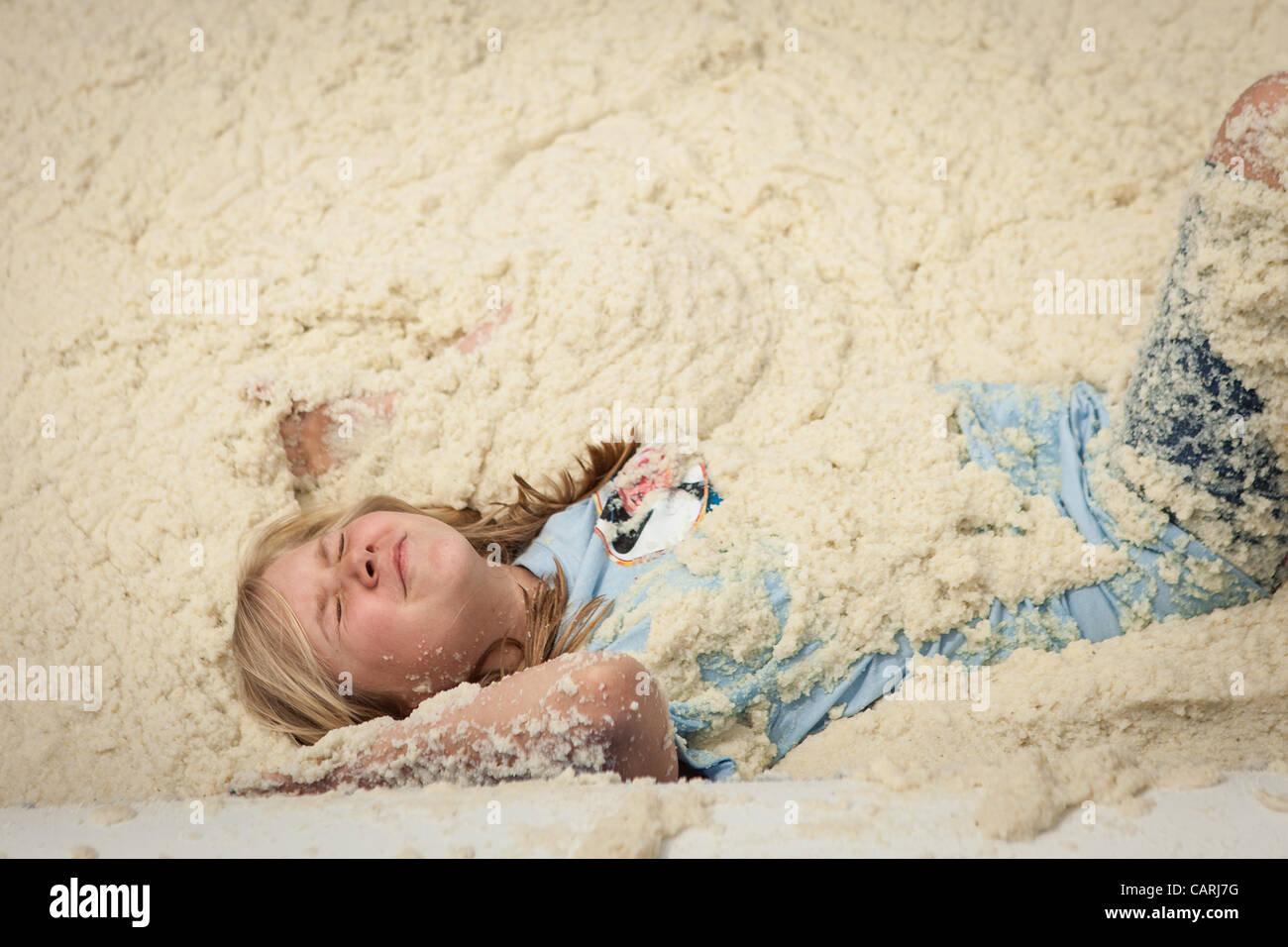 A competitor rolls around in a pool of instant grits during the grits