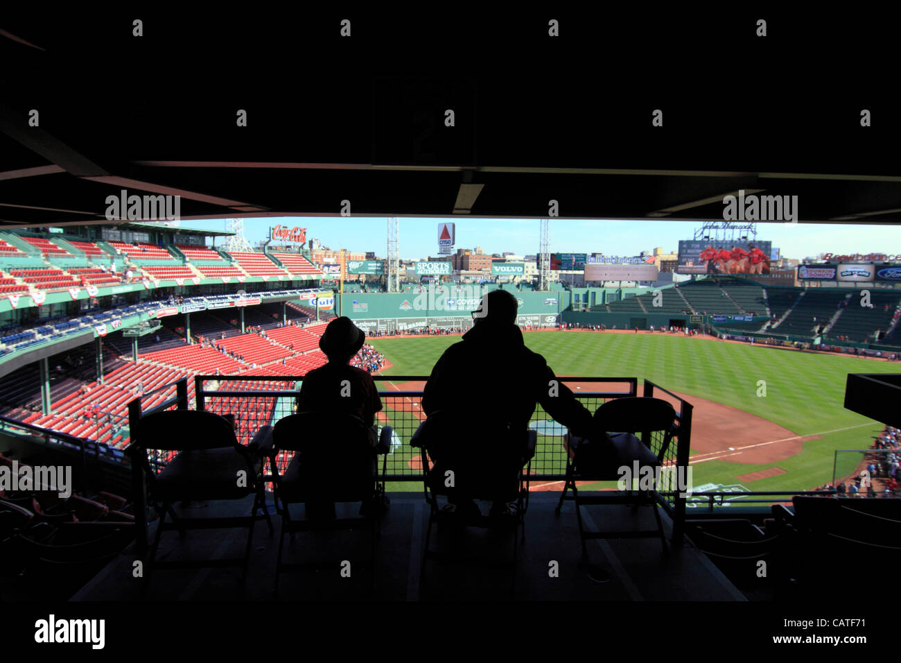 Boston, Massachusetts, USA. April 19, 2012. Silhouette of a Father and Son sharing a moment alone at Fenway Park on its 100th Anniversary whilst hundreds of Red Sox fans encircle the field to view the dugouts, the green monster and bullpens. Stock Photo