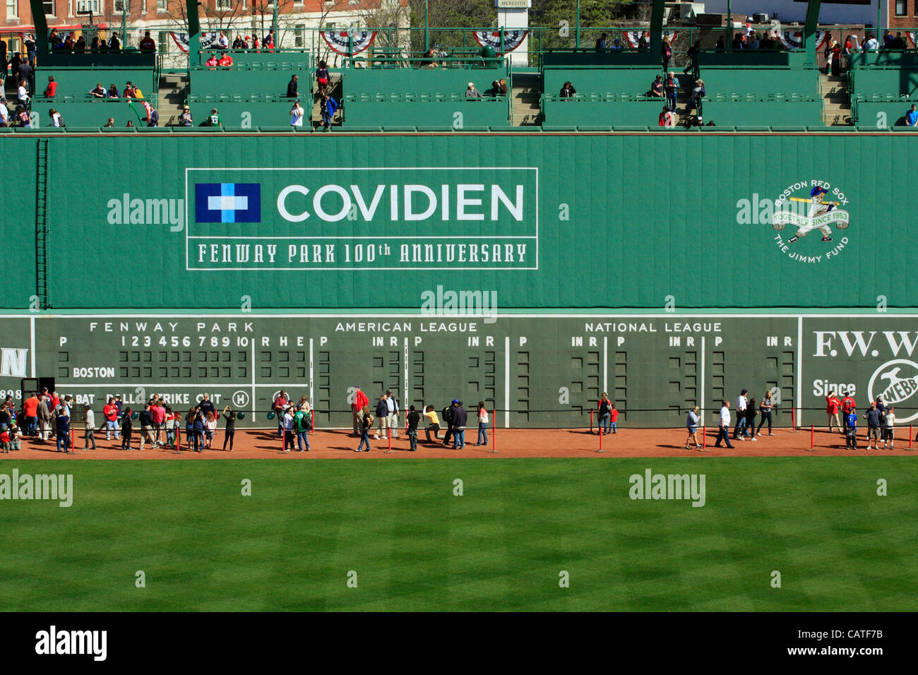 Boston, Massachusetts, USA. April 19, 2012. Dozens of Red Sox fans sit in the Green Monster Seats at Fenway Park on its 100th Anniversary Open House whilst hundreds walk on the warning track to get a closer look at the Green Monster wall and scoreboard in left field. Stock Photo