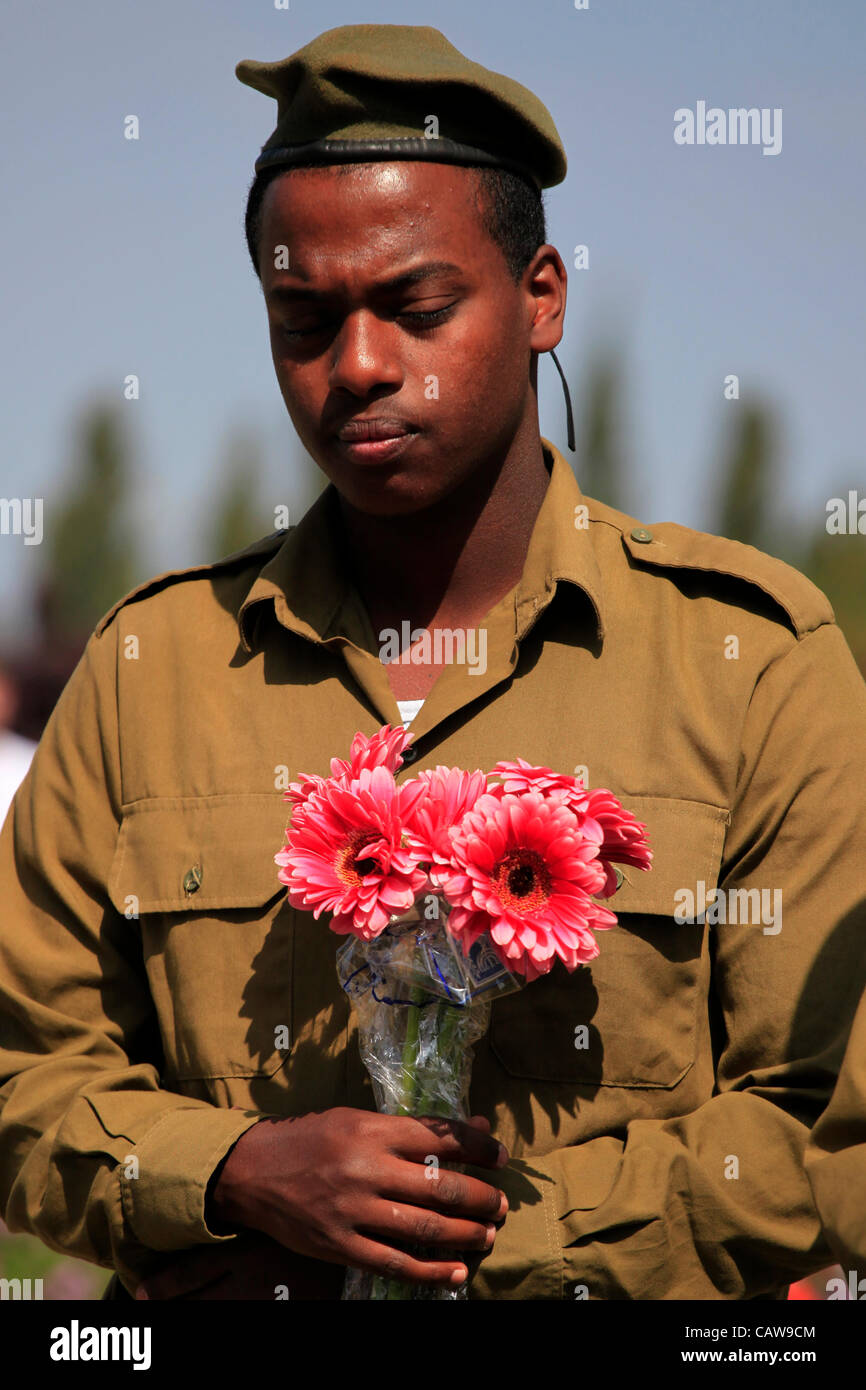 An Israeli soldier from the Beta Israel community also known as Ethiopian Jews holds flowers over the grave of a fallen soldier on Yom Hazikaron Memorial Day for the Fallen Soldiers in Kiryat Shaul Jewish burial ground in Northern Tel Aviv Israel Stock Photo
