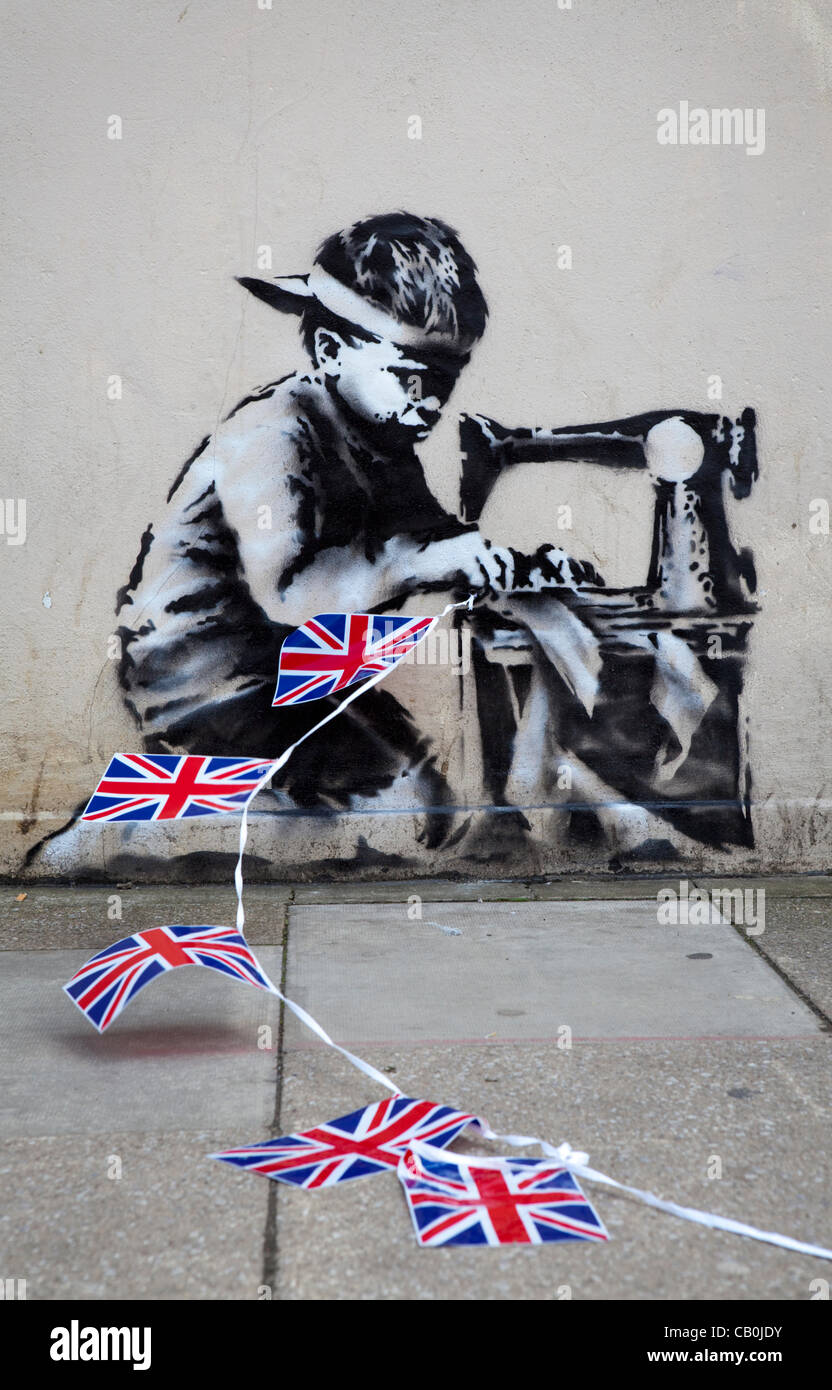 15/05/2012. A new work from Graffiti Artist Banksy has appeared overnight in London, UK. The piece depicts a Asian child stitching together Union Jack Bunting. The work on the wall of 'Poundland' is said to be Banksy's commentary on child labour and the upcoming Queen's Diamond Jubilee celebrations. Stock Photo