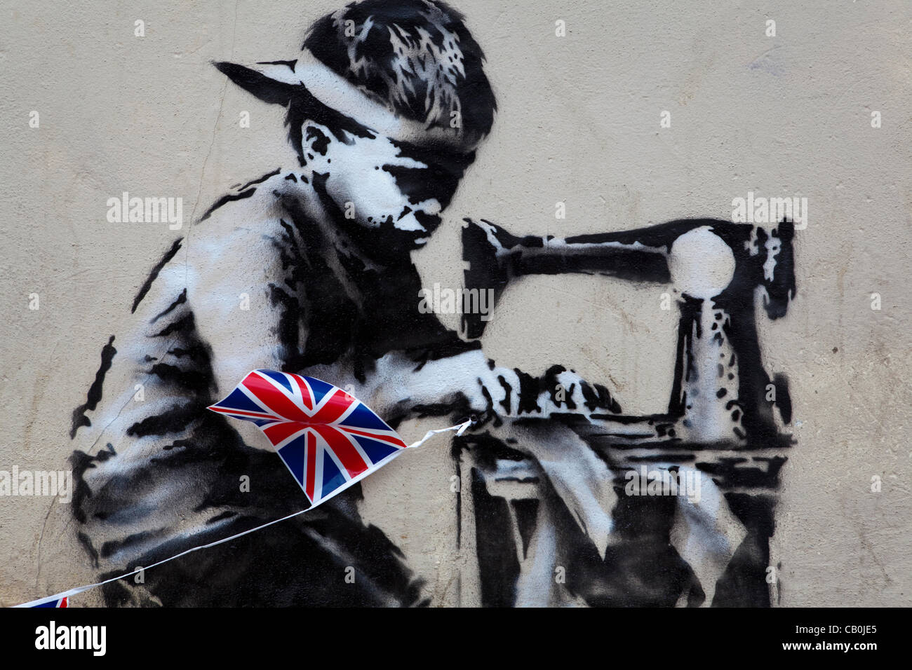 A new work from Graffiti Artist Banksy has appeared overnight in London. The piece depicts a Asian child stitching together Union Jack Bunting.  The work on the wall of retailer 'Poundland' is said to be Banksy's commentary on child labour and the upcoming Queen's Diamond Jubilee celebrations. Stock Photo