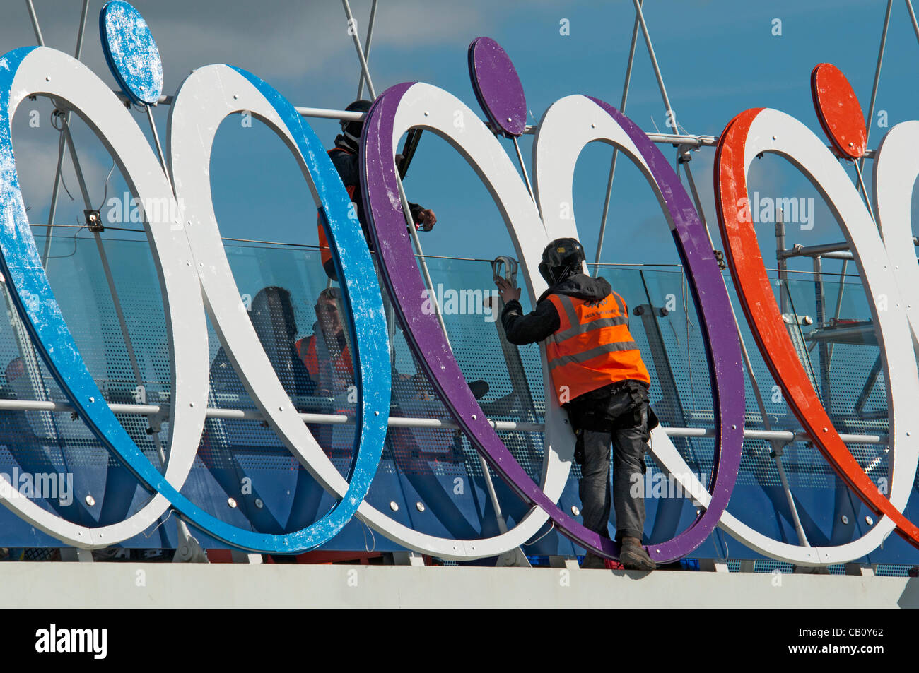 Workman installing an artwork on the Millennium (Lowry) footbridge in preparation for the Looping the Loop event at Salford Quays, held on Sat 19th May. The event marked the start of the London 2012 'Games Time' in North West England and the first day of the Olympic torch relay in the UK. Stock Photo