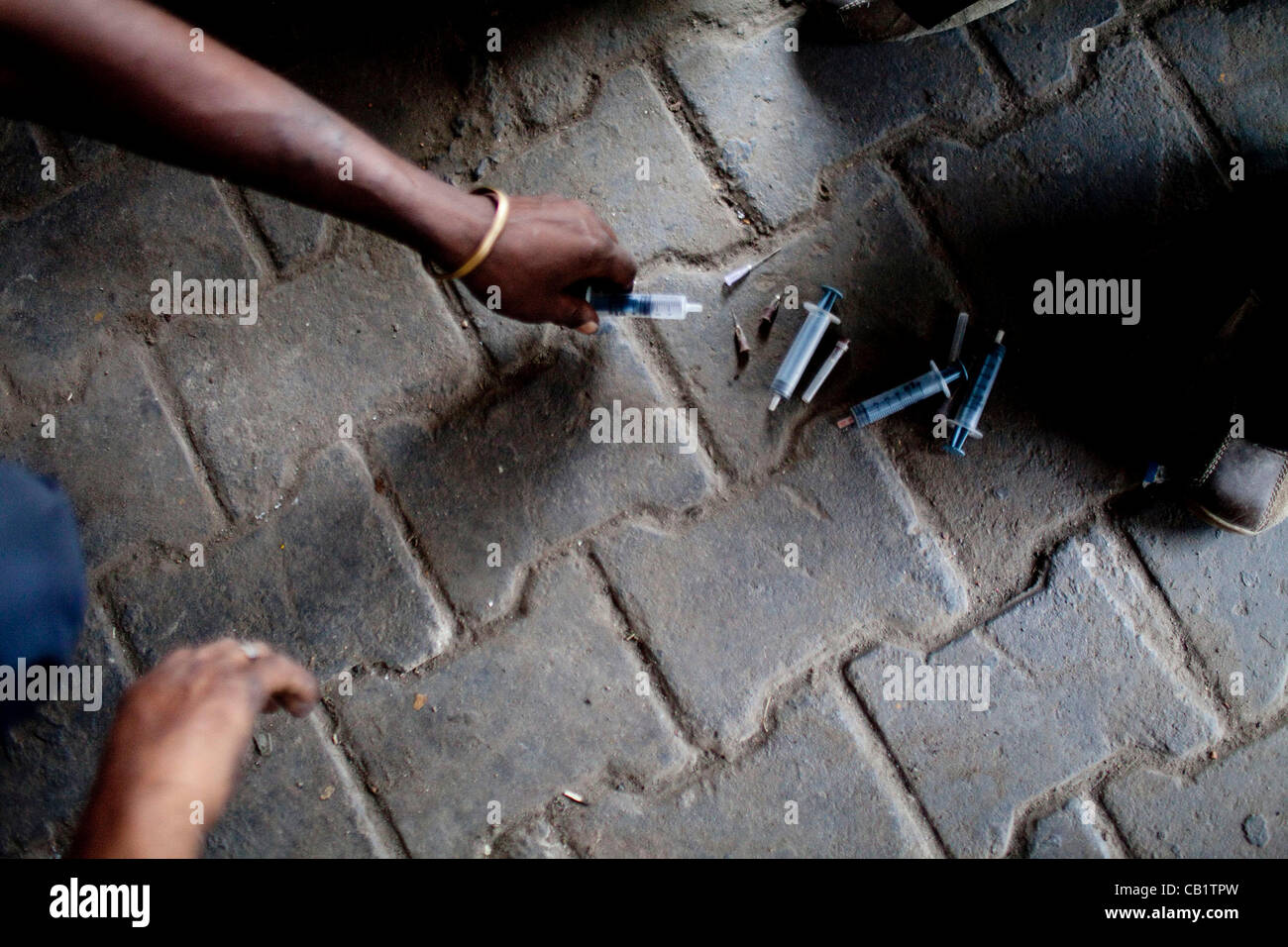May 16, 2012 - New Delhi, India - A drug addict places his used needle on the ground in order to receive a new one from NGO outreach workers in the Yamuna Bazaar. Approximately 1,200 drug addicts live on the streets in the bazaar, an area that is approximately two kilometers by two kilometers. (Cred Stock Photo