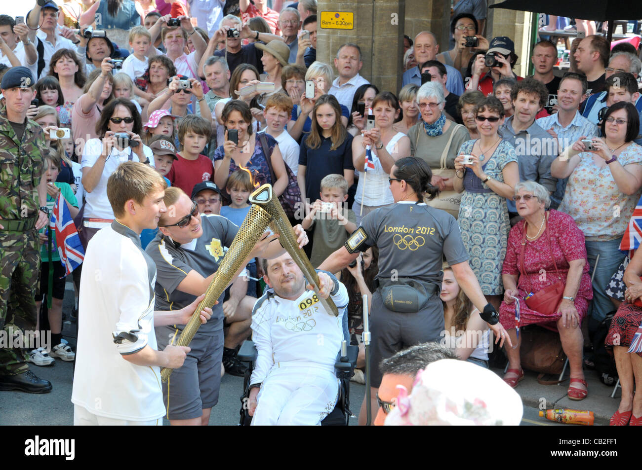 Thousands of people of all generations came together to celebrate the olympic torch passing through the the cotswold town of cirencester uk on wednesday 23rd may 2012.The sun shone to help create a really good party atmosphere.jake ashton year 10 deer park student hands the flame over to mark chard. Stock Photo