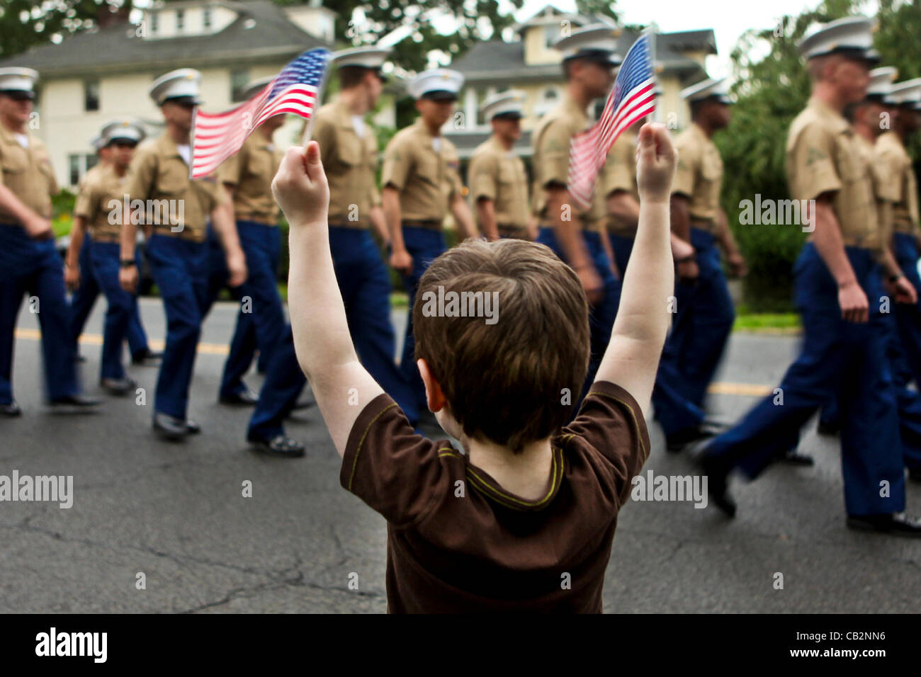 A small boy waves flags as US Marines march past in the Larchmont Memorial Day parade May 24, 2012 in Larchmont, NY. The US marks Memorial Day this weekend. Stock Photo