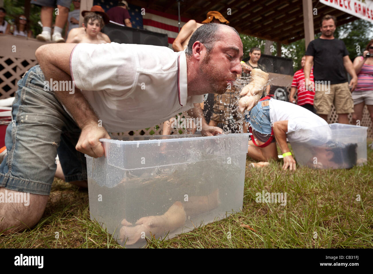 A competitor spits out a pigs foot during the dunking for pigss feet competition at the Red Neck Summer Games on May 26, 2012 in East Dublin, Georgia. Stock Photo