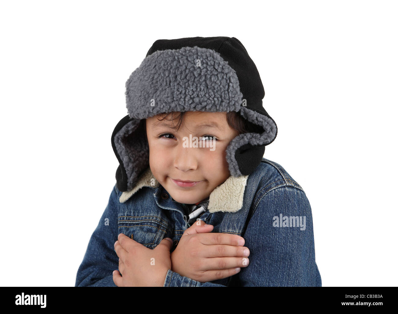 Boy freezing in the winter cold wearing woolen hat and jacket on white background Stock Photo