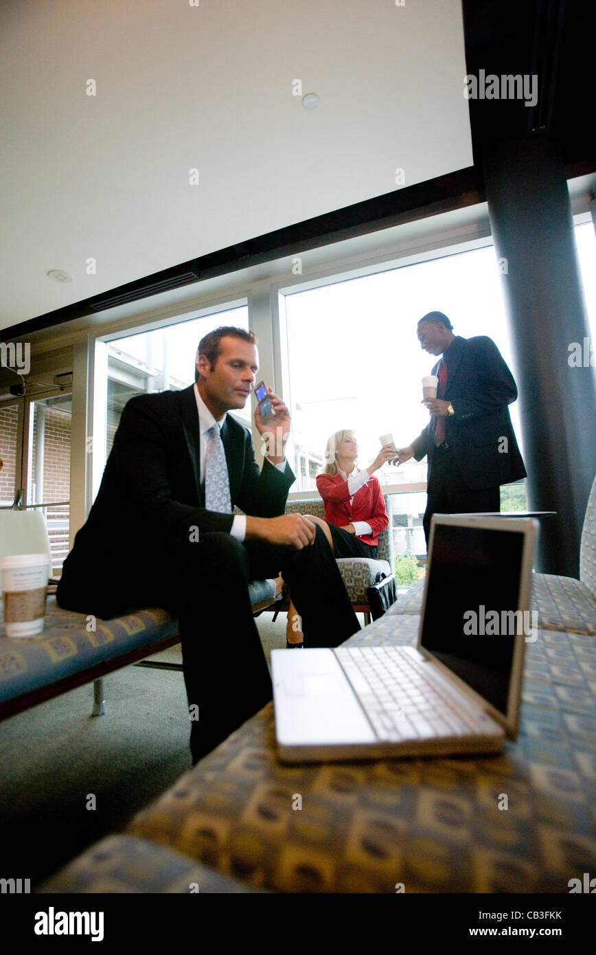Businessman on cell phone while his colleagues have coffee in the background Stock Photo