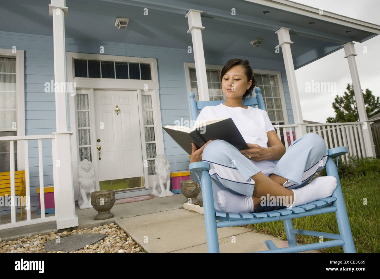 https://c8.alamy.com/comp/CB3G69/young-asian-woman-sitting-on-a-rocking-chair-reading-a-book-in-front-CB3G69.jpg