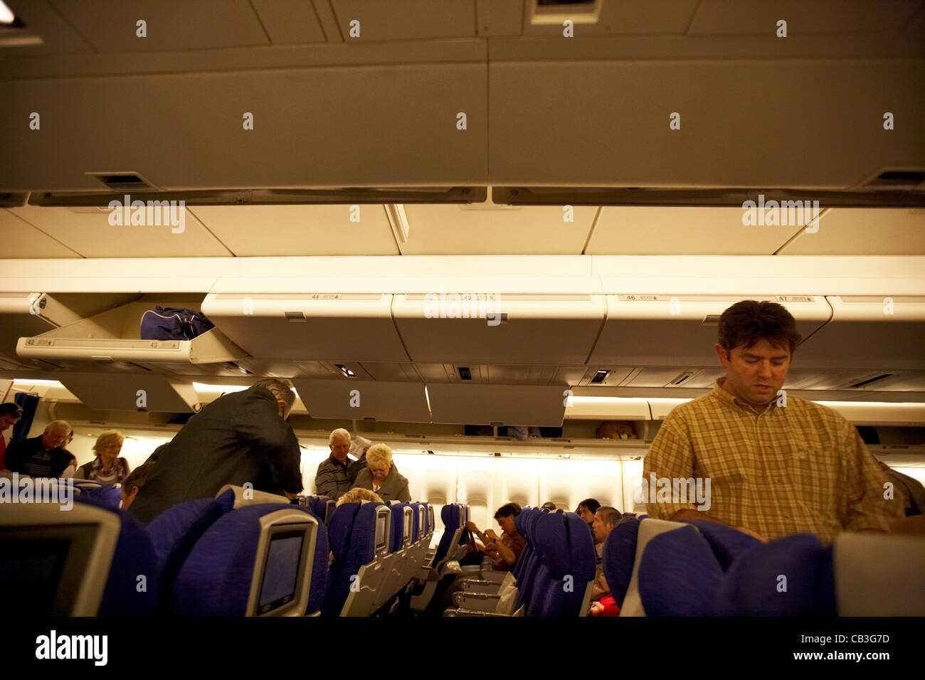 passengers boarding a 747 passenger aircraft filling up overhead lockers Stock Photo