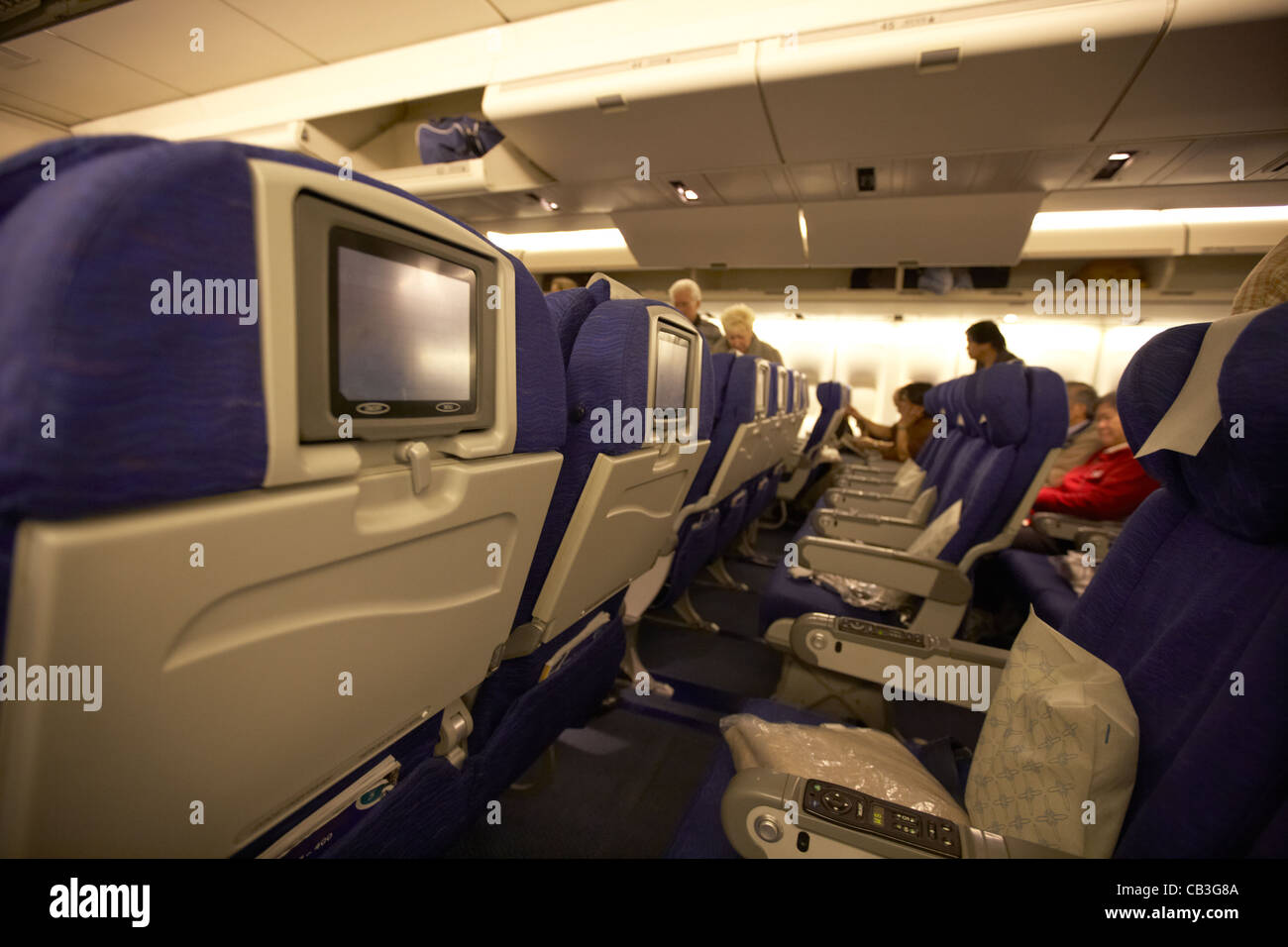 rows of seats with individual entertainment seat back screens on board a 747 passenger aircraft Stock Photo