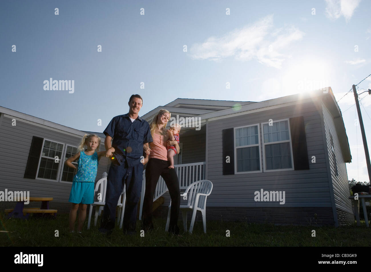 Portrait of a bluecollar family standing in front of a trailer home