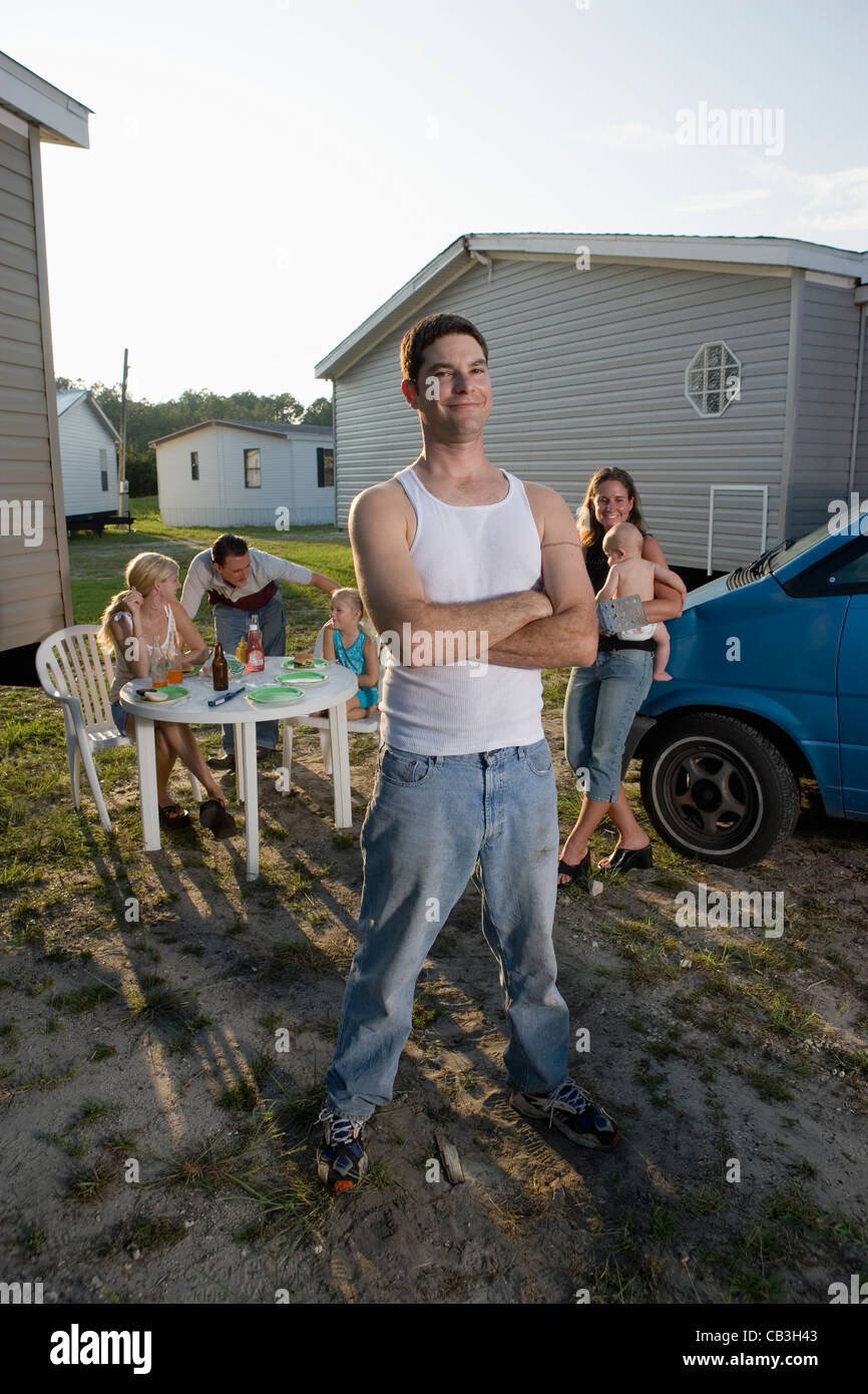 Portrait a blue-collar man with his family and friends in front of trailer homes Stock Photo