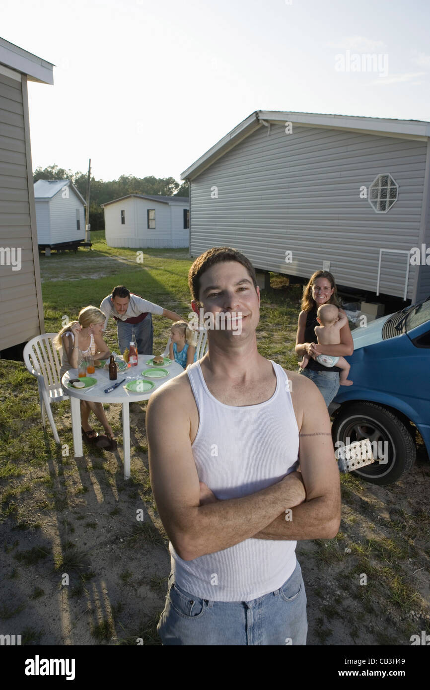 Portrait a blue-collar man with his family and friends in front of trailer homes Stock Photo