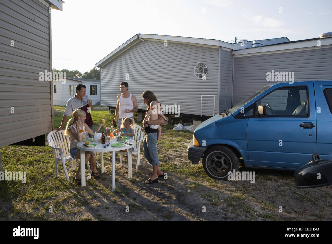 Blue collar families enjoying lunch in front of trailer home Stock Photo