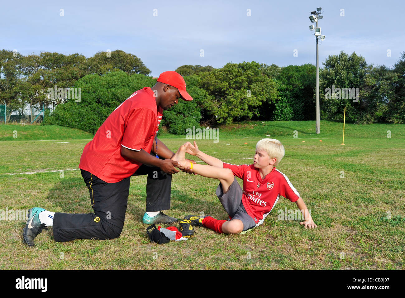 Football coach evaluates the injury of a youth team player Cape Town South Africa Stock Photo