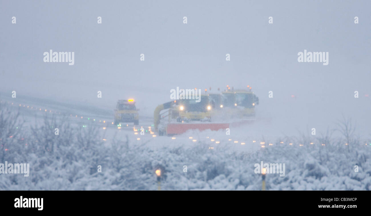 Snowploughs battle to clear thick snow from London Gatwick Airport's runway during a blizzard. Stock Photo