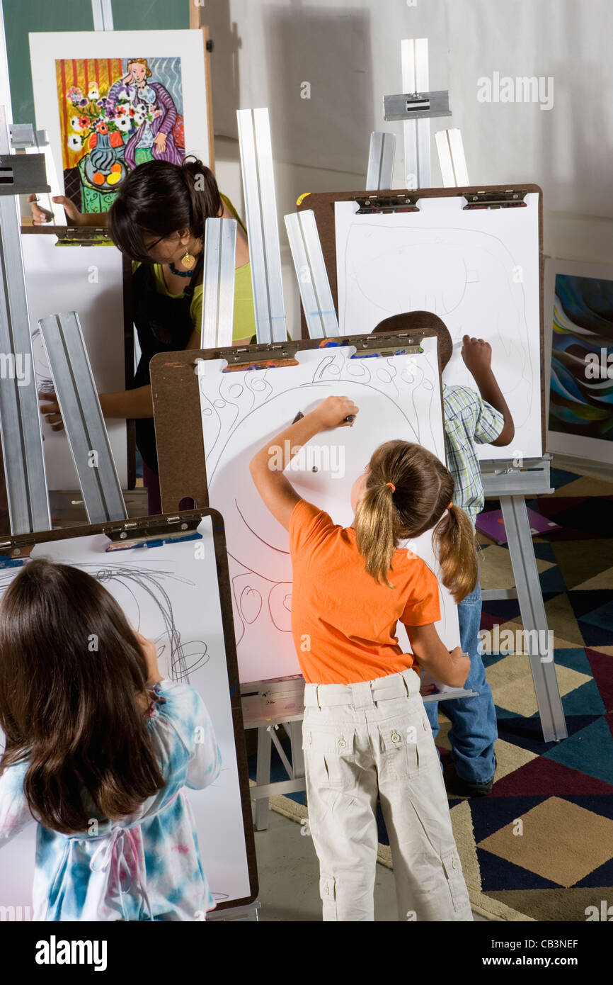 An art teacher with her students drawing on easels in art class Stock ...