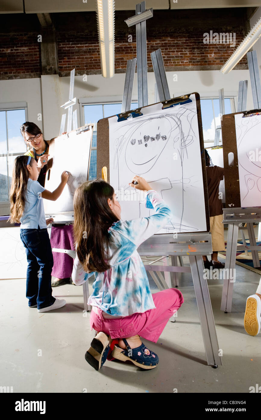 An art teacher with her students drawing on easels in art class Stock ...