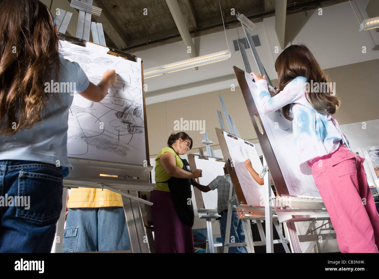 An art teacher with her student drawing on easels in art class Stock ...