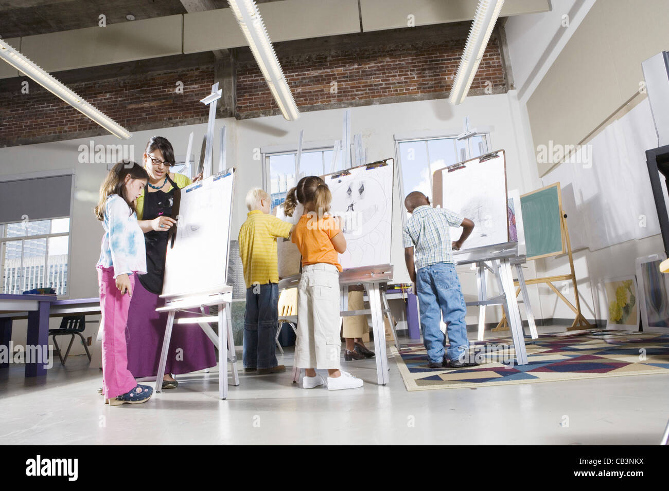 An art teacher with her student drawing on easels in art class Stock ...