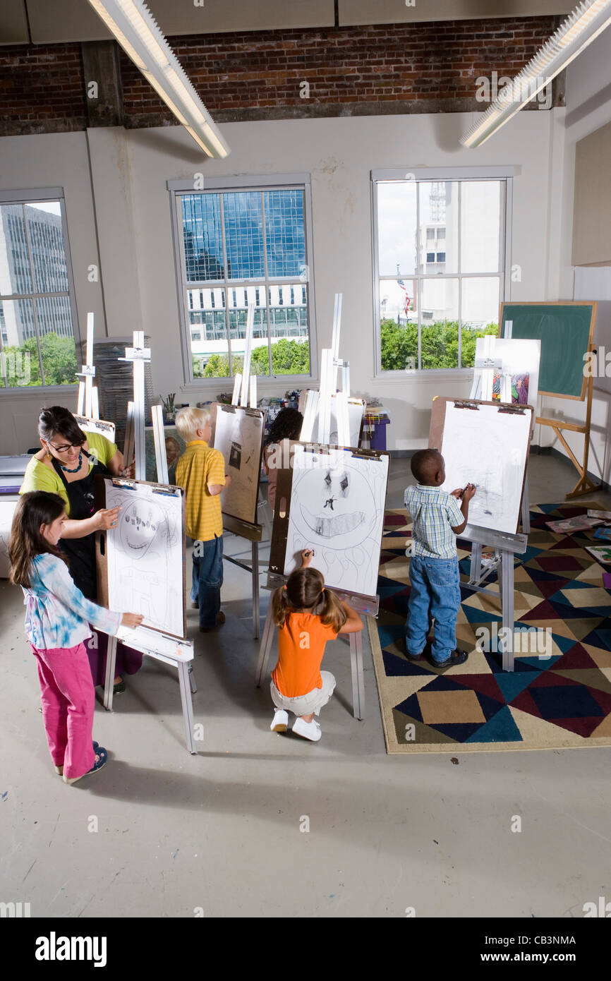 An art teacher with her student drawing on easels in art class Stock ...
